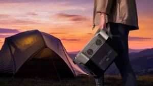 Man carrying a portable power station to his tent while the sun sets.